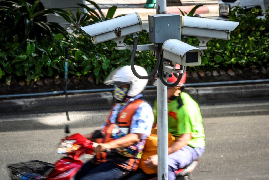 A closed circuit TV (CCTV) system is seen as a motorcycle taxi rider ferries a passenger in Bangkok. Source: AFP