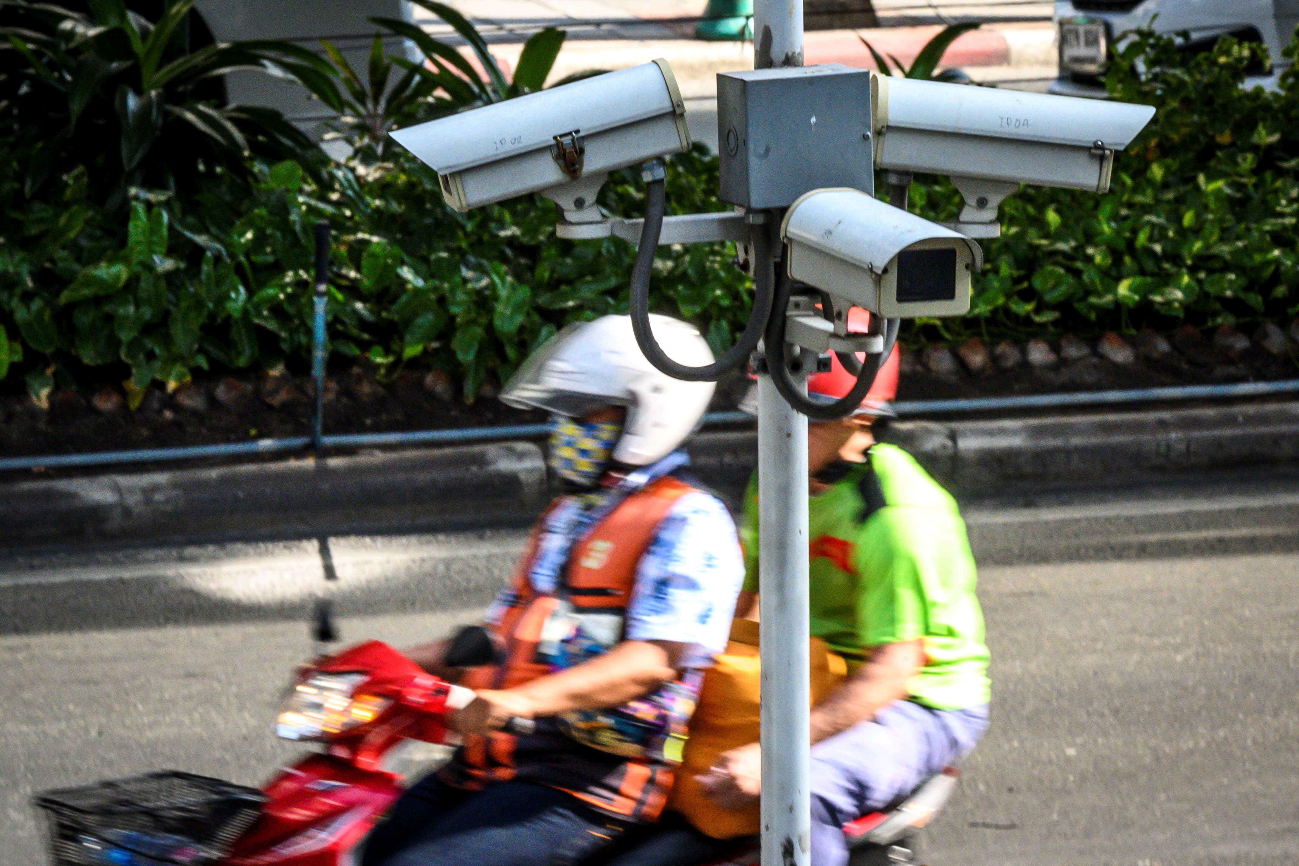 A closed circuit TV (CCTV) system is seen as a motorcycle taxi rider ferries a passenger in Bangkok. Source: AFP
